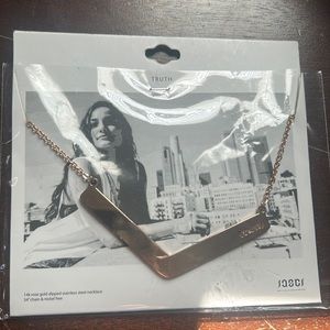 Long gold tone necklace with “truth” cutout
